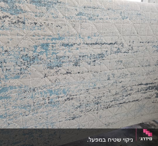 שטיח עם דוגמה כחולה ולבנה על רצפה אפורה